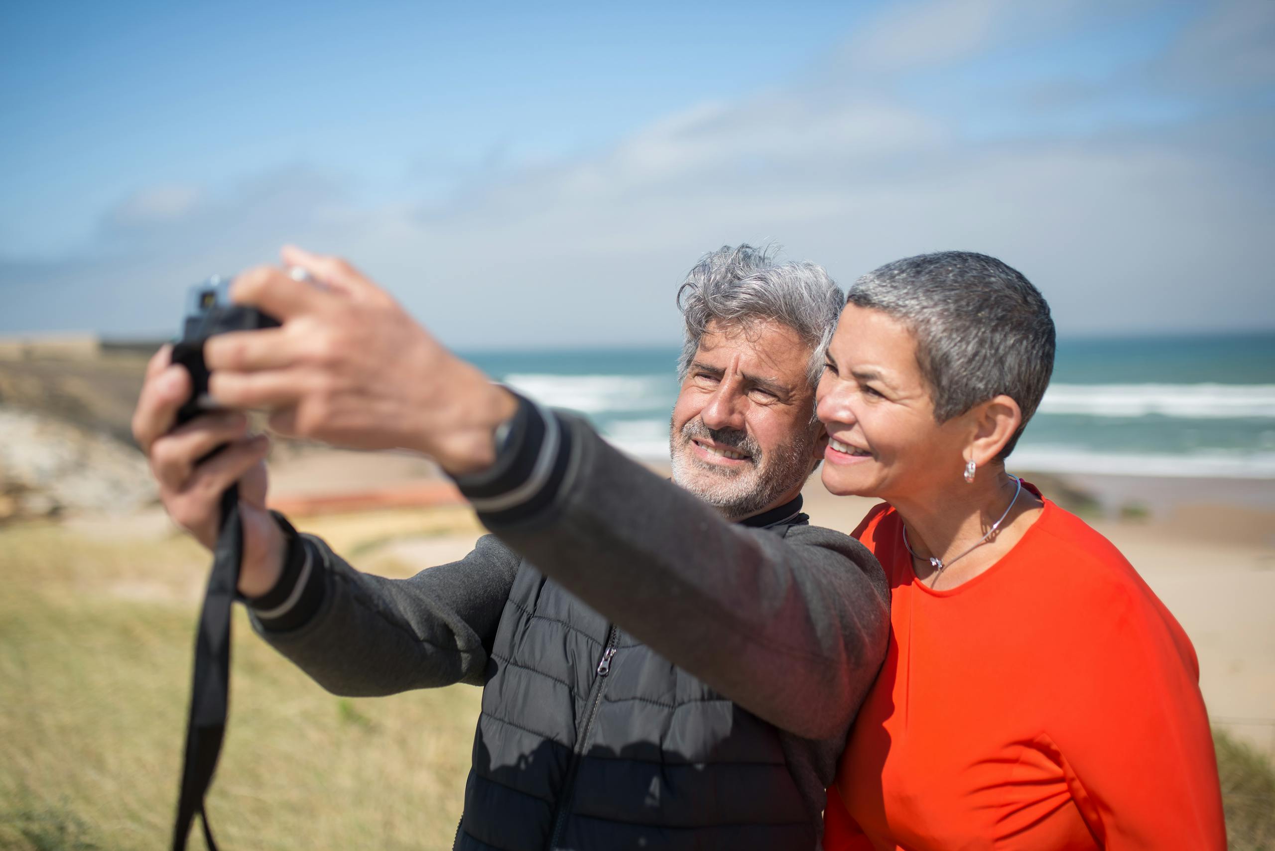 Happy older couple on the beach taking a selfie